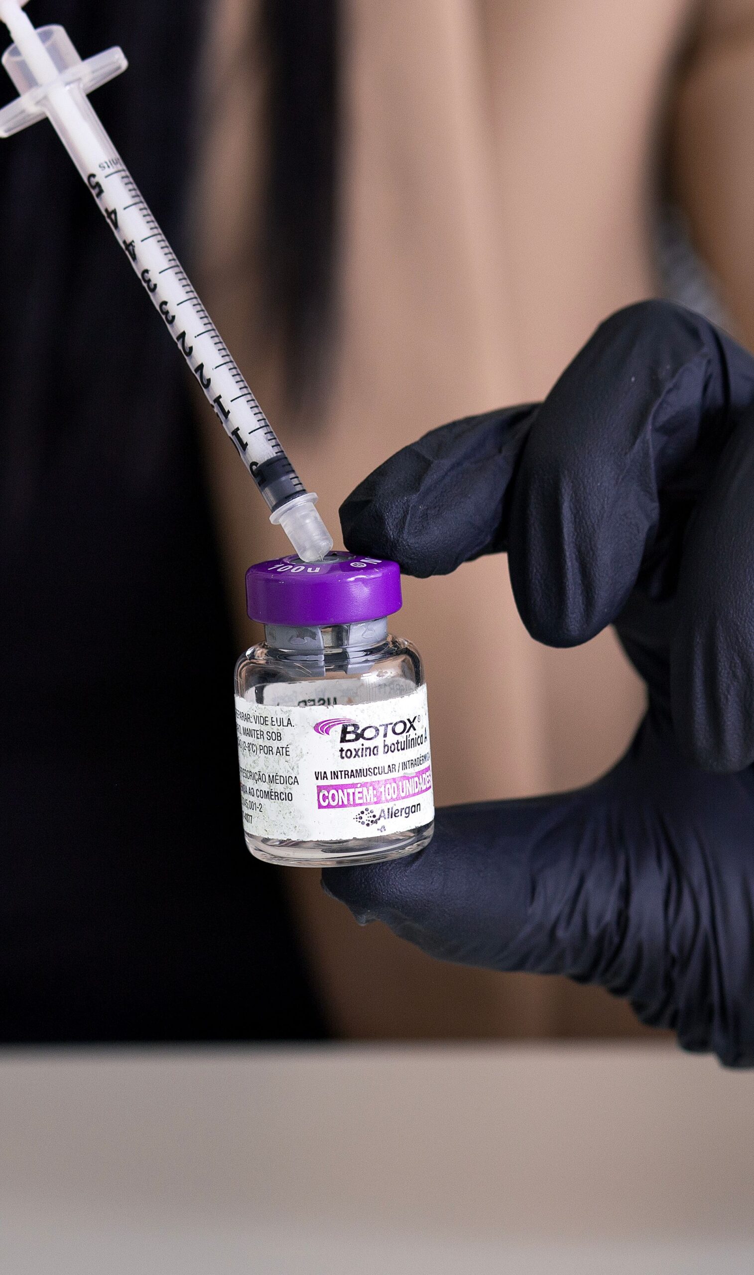 Close-up of a syringe and Botox vial handled by medical professional.
